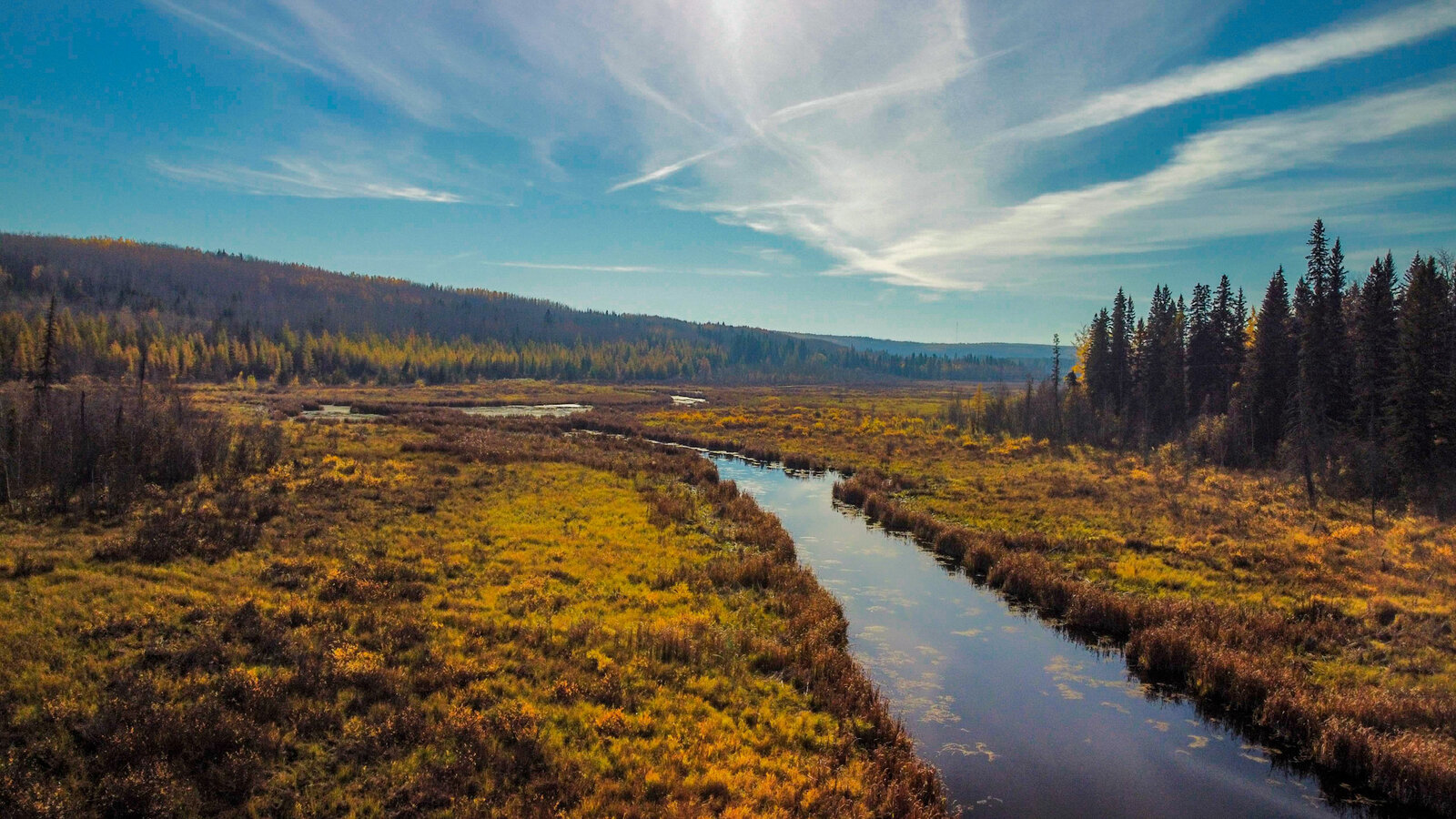 Aerial view of a meandering river through autumn meadow under big sky